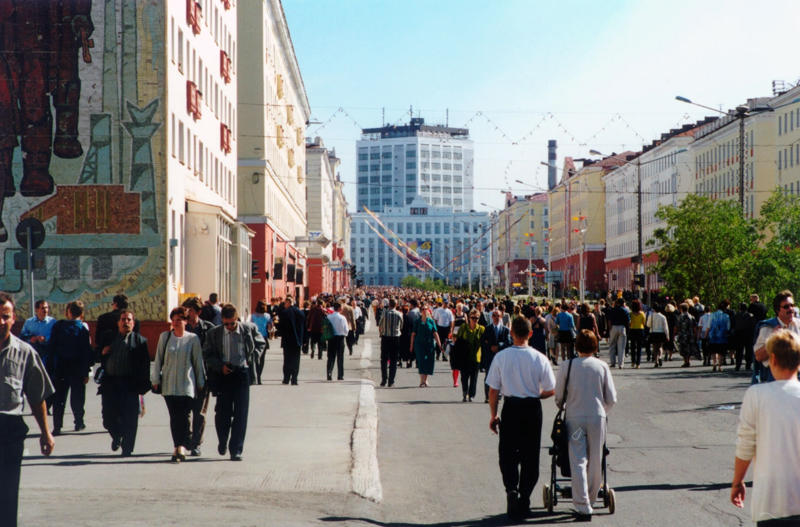 people walk along a sunny street in norilsk's city center